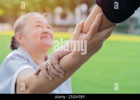Hand of nurse helping senior Asian woman to exercise and holding hands at park. Selective focus. Stock Photo