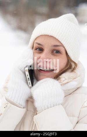 Caucasian woman with braces on teeth talking on phone outdoors in winter.  Stock Photo