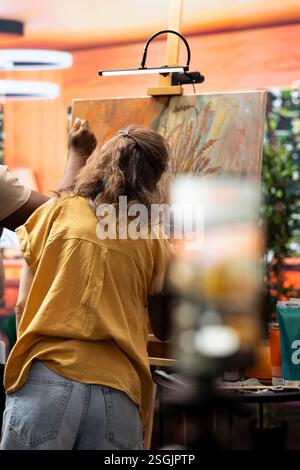 Skilled painters working together on an artwork in artistic workshop, recording an online tutorial for e learning virtual classroom. Creating a masterpiece and documenting the process for art lesson. Stock Photo