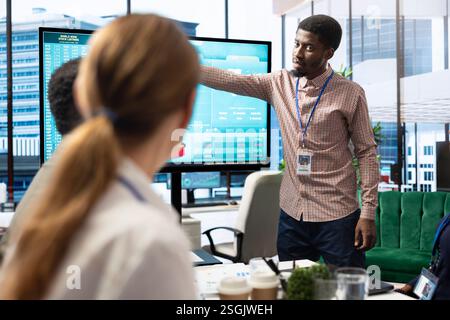 Diverse work team discussing digital marketing trends on interactive board, using analytics to improve sales numbers in a meeting. Business experts developing a startup company. Stock Photo