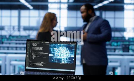 Close up of laptop with AI technology used to sustain data center hardware. Focus on notebook used by server room programmers in background using artificial intelligence tech, camera A Stock Photo