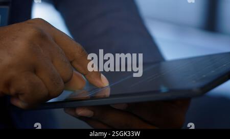Software developer doing yearly maintenance using tablet to prolong data center equipment life span. Extreme close up of worker in server hub monitoring server infrastructure using device, camera A Stock Photo