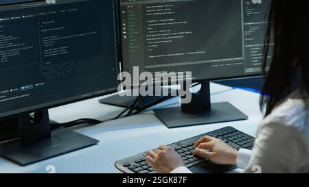 Computer scientist in data center monitoring security threats using PC, implementing cybersecurity measures. Server farm employee ensuring compliance with regulations, camera A Stock Photo