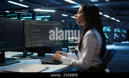 Data center call center agent responsible for providing logistics support to businesses. Worker in server farm establishment oversees infrastructure systems and communicates with engineers, camera B Stock Photo