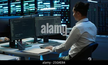 Data center system administrator responsible for installation of networking equipment solving tasks. IT employee at work doing maintenance on server room hardware, camera A Stock Photo
