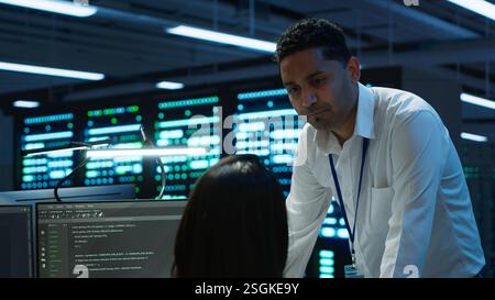Team of admins in data center ensuring system can handle networking tasks. Teamworking colleagues in server room tracking network traffic with PC, making improvements, camera A Stock Photo