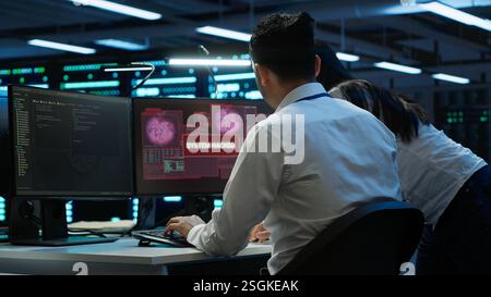 Computer scientists in server room protect hardware from hacker attack stealing sensitive information. Data center cybersecurity division teamworking colleagues fighting security breach, camera A Stock Photo