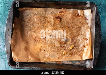 Baking tray with used baking paper. The texture of dirty parchment on a dark green background. High quality photo Stock Photo