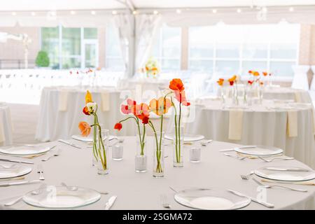Wedding reception table with white linens and tall poppy flowers. Stock Photo
