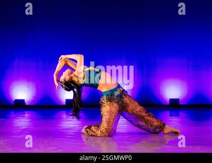 Dancer in colorful costume performs on stage with vibrant blue and purple lighting. The Nutcracker, Bainbridge Island, USA Stock Photo