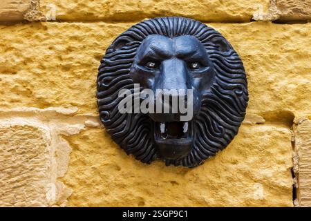 Black Lion Head Sculpture on Yellow Bricked Background Wall Stock Photo