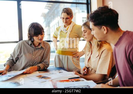 Teacher and students collaborating on a project in a bright, modern classroom. Focus on teamwork and communication. Stock Photo