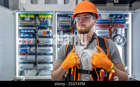 Electrician man in overalls works in the switchboard. Portrait of an electrician in overalls. Stock Photo