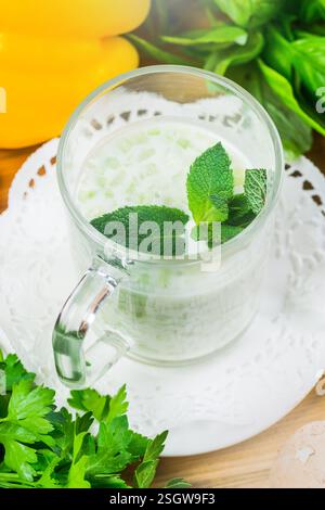 Refreshing drink with mint leaves and herbs served in a clear glass on a wooden table Stock Photo