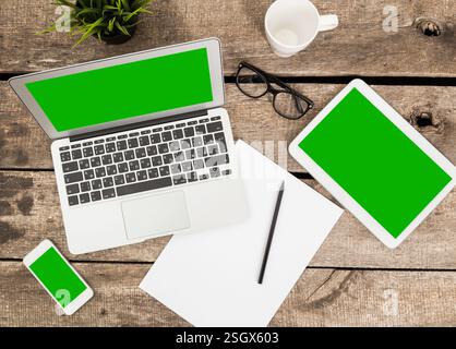 Workspace with multiple devices and stationary on a wooden table during the day Stock Photo