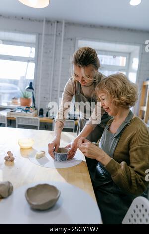 Happy retired student learns new skills, creating a handmade ceramic bowl Stock Photo