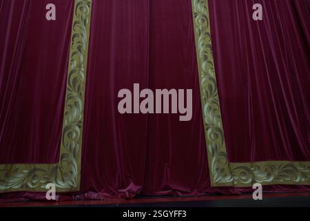 A red curtain with vertical pleats, illuminated in a theatrical setting, showcasing the rich dense texture of the fabric with room to copy. High quality photo Stock Photo