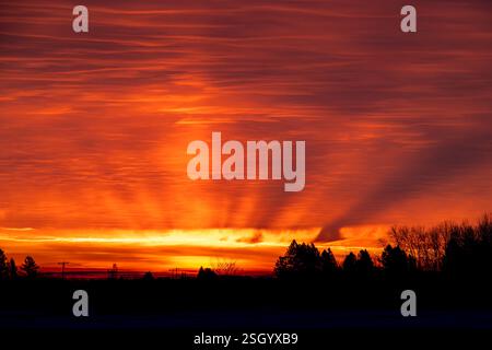 Red sunrise with sun beams coming through the clouds. Winter morning. Stock Photo