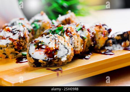 Deliciously crafted sushi rolls with crispy tempura coating served on a wooden platter in a casual dining setting Stock Photo