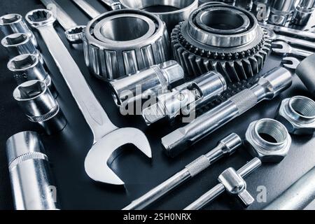 Variety of metallic tools and gears arranged on a surface in a well-lit workshop setting Stock Photo