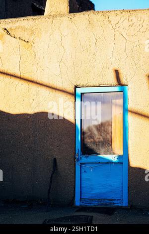 Charming Blue Door on Adobe Wall with Shadows and Textures Stock Photo
