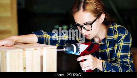 Female handy person repairing crate using screwdriver Stock Photo
