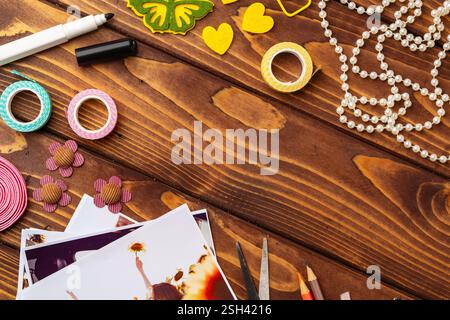 Creative crafting workspace with colorful supplies and printed photographs arranged on wooden table Stock Photo