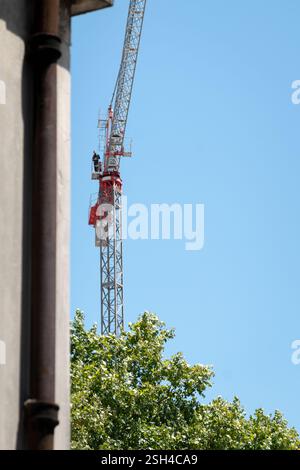 Operator working at height on a large construction cranes with blue sky in the background. Stock Photo