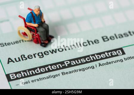 Steuererklärung für Finanzamt Auf einem Steuerformular über außergewöhnliche Belastungen für das Finanzamt steht ein Modell-Rollstuhl Stock Photo