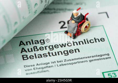 Steuererklärung für Finanzamt Auf einem Steuerformular über außergewöhnliche Belastungen für das Finanzamt steht ein Modell-Rollstuhl Stock Photo