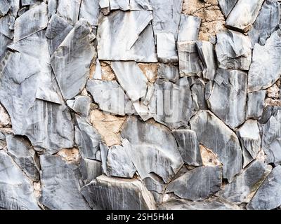 textured background - wall covered with fragments of gray rock Stock Photo