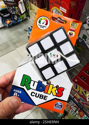 Kyiv, Ukraine - February 09, 2025: Hand holding Rubik's Cube box, showcasing puzzle toy shelf in a store. Stock Photo