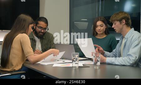 Diverse businessmen businesswomen team review sales data documents paperwork teamwork discussion multiracial business men women colleagues coworkers Stock Photo