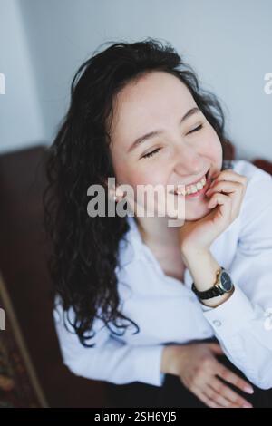 A cheerful young woman with beautiful curly hair beams with a bright smile, radiating genuine happiness and positivity Stock Photo