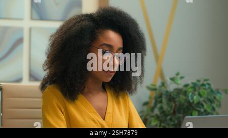 Smiling African American woman ethnic student businesswoman office manager employer typing laptop computer at workplace online chatting with clients Stock Photo