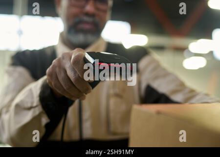 Focus on hand of warehouse manager scanning barcodes on packed cardboard boxes while checking information Stock Photo