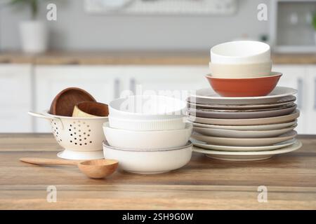 Different plates and bowls on wooden table in kitchen Stock Photo