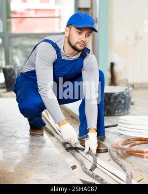 Man electrical installer laying cables through trench Stock Photo