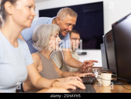 Older mentor explaining something to elderly woman during computer class Stock Photo
