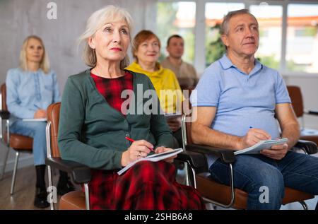 Group of older students sitting and listening at lesson Stock Photo