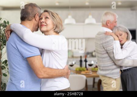 Two married couples enjoying slow dancing at house party for friends Stock Photo