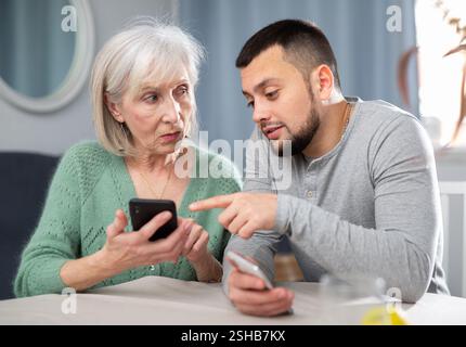 Man teaching his aged mother to use smartphone Stock Photo