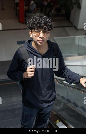 A young man wearing a blue suit on an electric escalator, ideal for themes like fashion, urban life, transportation, and modern lifestyle. Stock Photo