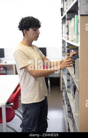 A student studying in a library surrounded by books and notes. Perfect for themes like education, studying, academic focus, and university life. Stock Photo