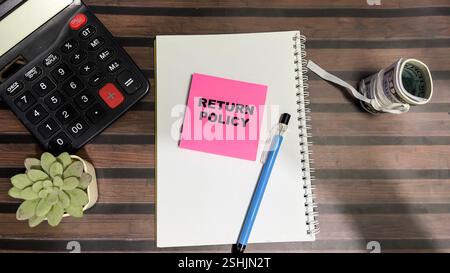 Concept of Return Policy write on sticky notes isolated on Wooden Table. Stock Photo