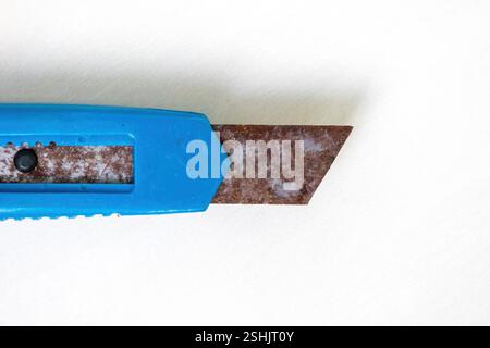 Close-up of an old, unused blue cutter knife with rust, isolated on a white background. Top view. Stock Photo