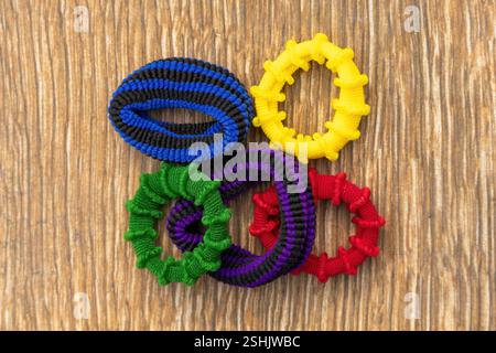 Colorful scrunchies on a wooden background. These are fabric-covered elastic hair ties used to fasten hair. Top view. Stock Photo
