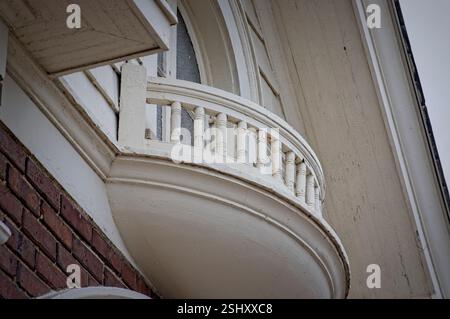 Wood and concrete balcony in front of upper level window on old brick building Stock Photo