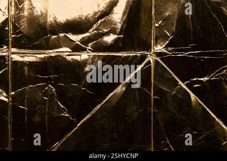 Wrinkled gold foil with deep creases and sharp folds reflecting light. Luxury metallic grunge background. Texture imperfections Stock Photo