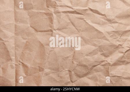 Wrinkled recycled kraft paper surface with creases and fold. Eco-friendly textured crumpled brown background for packaging. Close-up Stock Photo